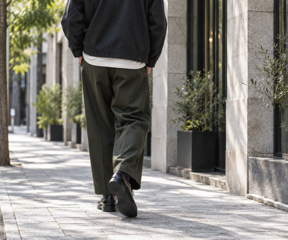 ワイドパンツと黒の革靴を合わせて街を歩く男性の後ろ姿